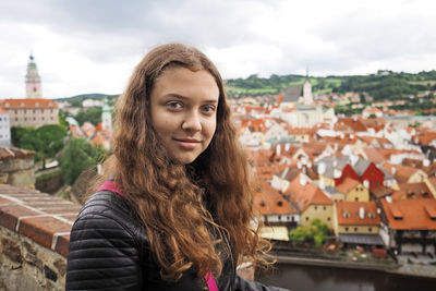 Portrait of beautiful woman in city against sky