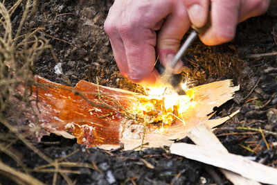 Close-up of hand igniting wood