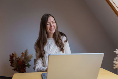 Young woman using laptop at home having conversation