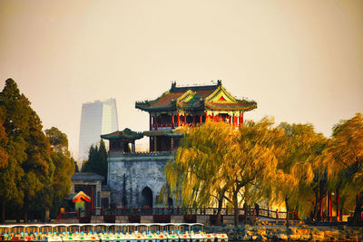 Traditional building by trees against clear sky