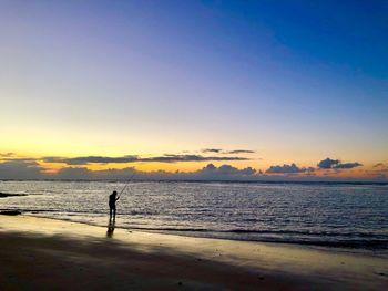 Silhouette person standing on beach against sky during sunset