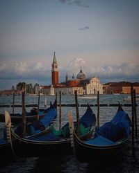 Boats moored at dock against sky in city