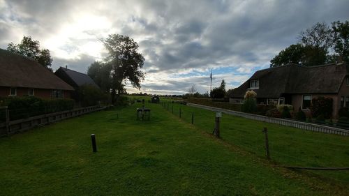 Scenic view of field by houses against sky