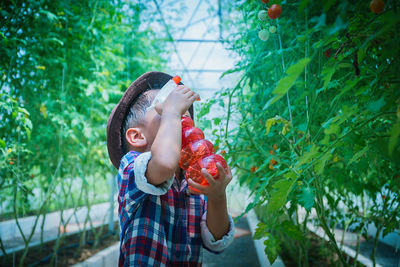 Midsection of girl holding plant against trees