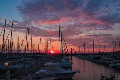 Sailboats moored at harbor during sunset