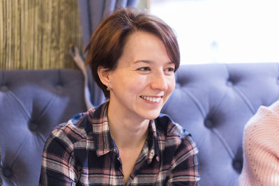 Portrait of smiling young woman sitting on sofa at home