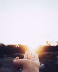 Midsection of person against sun during sunset