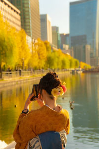 Rear view of man photographing by lake