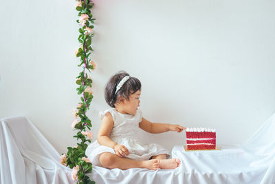 Cute girl sitting on white wall