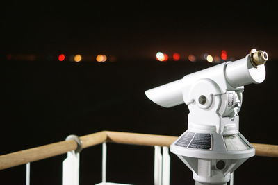 Close-up of coin-operated binoculars at observation point during night