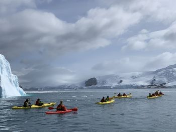 People kayaking on sea against sky