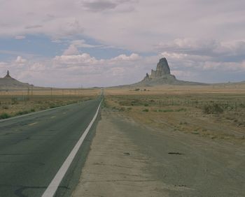 Road leading towards mountains against sky