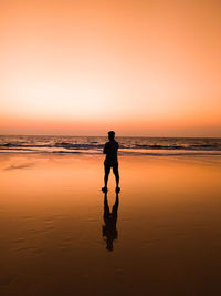 Silhouette man standing on beach against sky during sunset