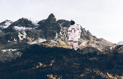 Rear view of woman standing on mountain against sky