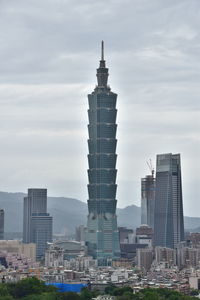 Buildings in city against cloudy sky