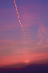 Low angle view of vapor trail in sky during sunset