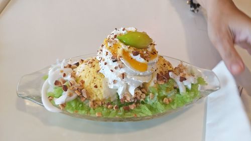 Close-up of hand holding ice cream served on table