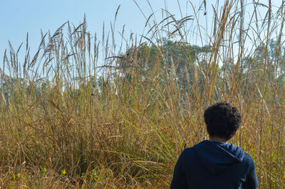 Rear view of man standing on field against sky