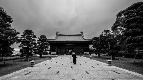 Rear view of man walking on street against sky