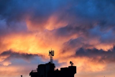Low angle view of silhouette building against sunset sky