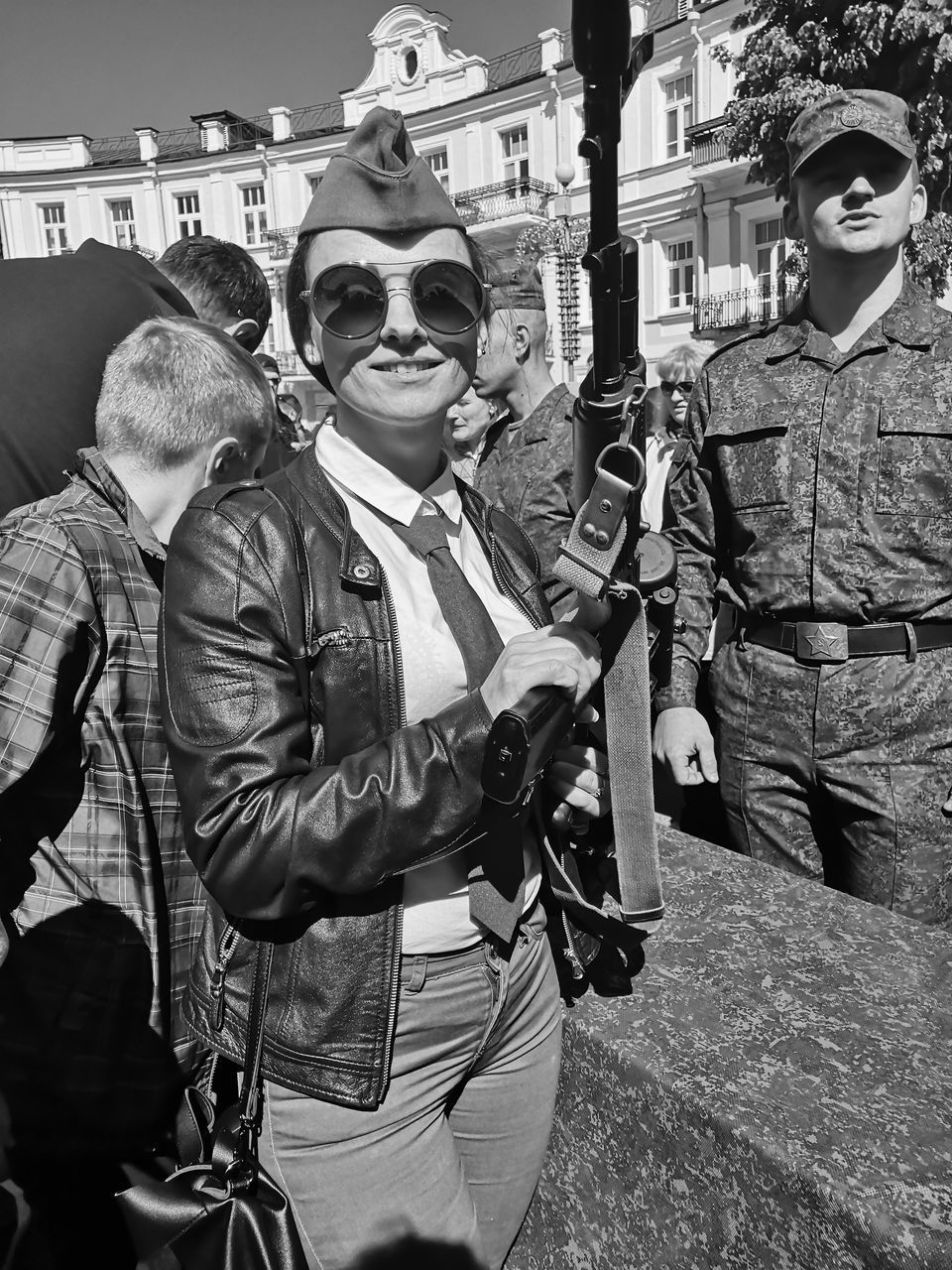 real people, men, city, street, clothing, people, day, three quarter length, architecture, group of people, incidental people, standing, young men, outdoors, weapon, built structure, lifestyles, sunglasses, casual clothing, adult, uniform