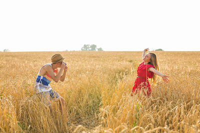 Side view of young couple on field against sky
