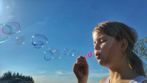 Low angle view of girl blowing bubbles using wand