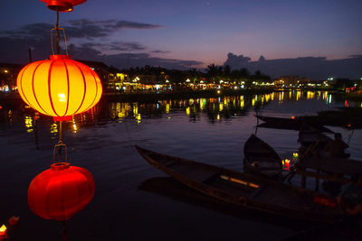 Reflection of illuminated lights in lake at sunset