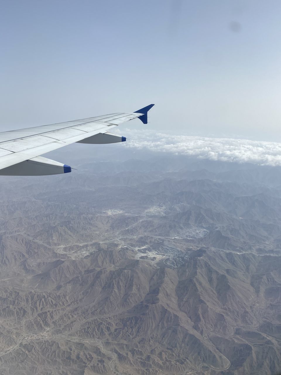 AERIAL VIEW OF AIRPLANE FLYING OVER MOUNTAINS AGAINST SKY