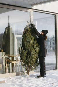 Woman preparing christmas tree in front of house