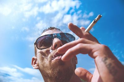 Man smoking against blue sky