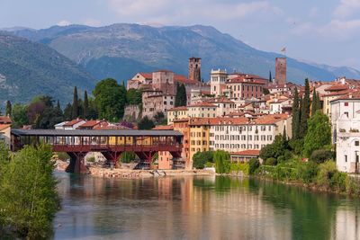 Bridge over river by buildings in city against sky