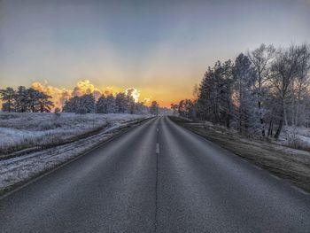 Road amidst trees against sky during winter