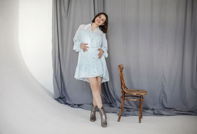 Portrait of young woman standing against wall