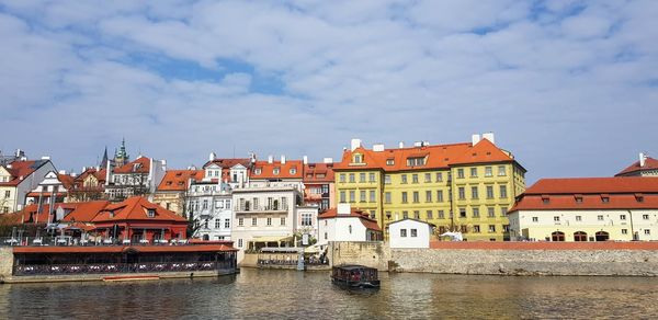 Buildings by river against sky in city