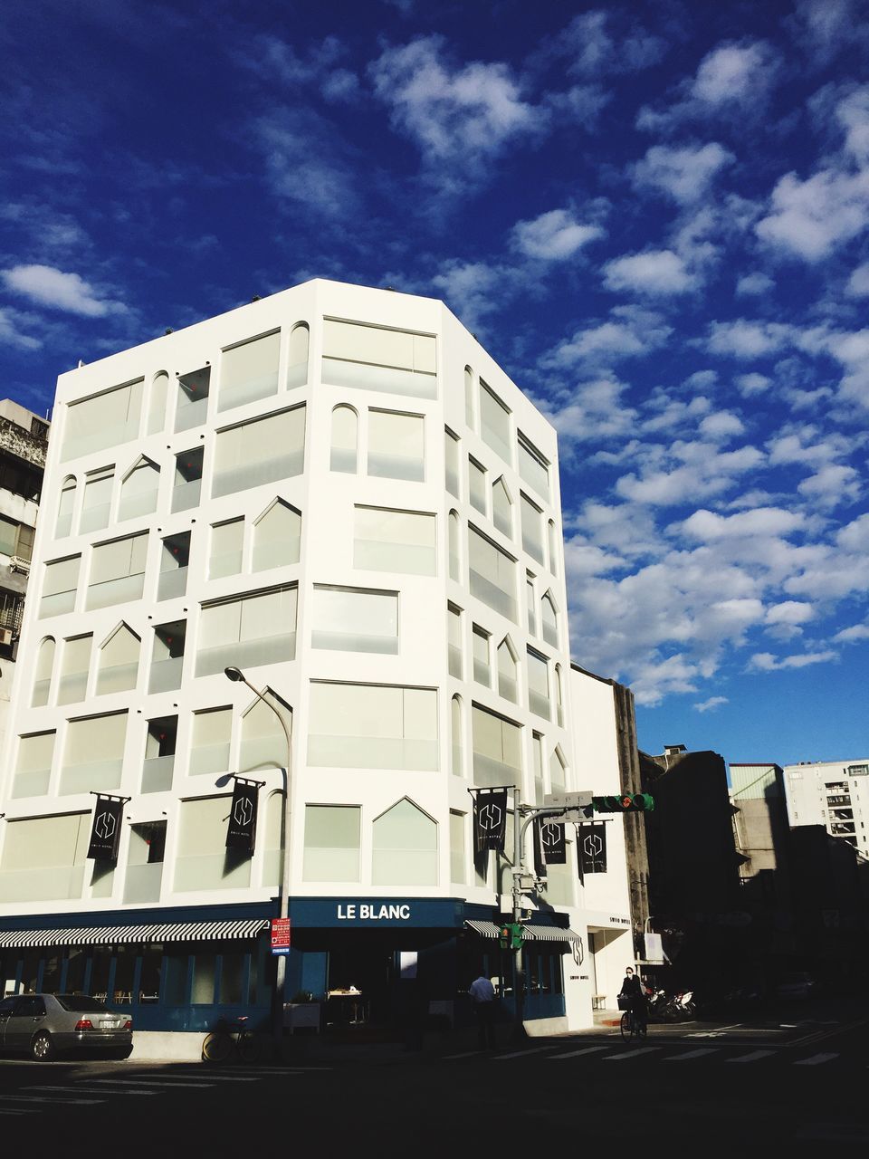 architecture, building exterior, built structure, car, transportation, land vehicle, sky, mode of transport, city, street, cloud - sky, road, building, low angle view, modern, cloud, city life, window, day, office building