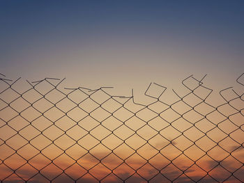 Old wire mesh fence texture against sunset sky background