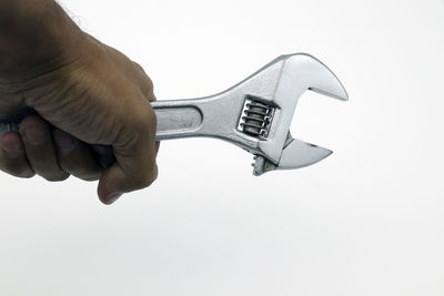 Close-up of hand holding object over white background