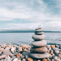 Stack of stones on beach against sky