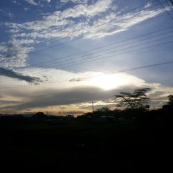 Electricity pylon against cloudy sky