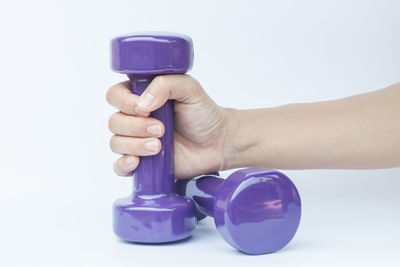 Close-up of hand holding purple against white background