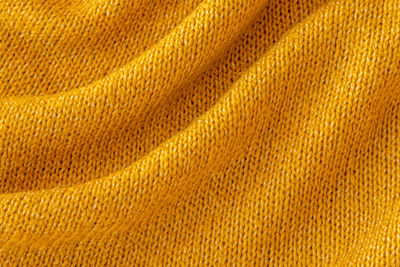 Soft knitted yellow sweater texture. orange abstract background. trendy mustard-colored backdrop