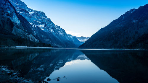 Scenic view of lake and mountains against clear blue sky