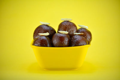 Close-up of fruit in bowl against yellow background