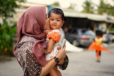 Close-up of mother kissing daughter on road