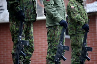 Midsection of men with weapons in camouflage clothing