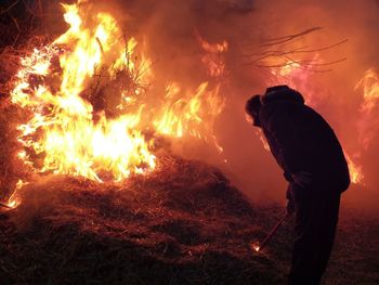 Man burning hay at night