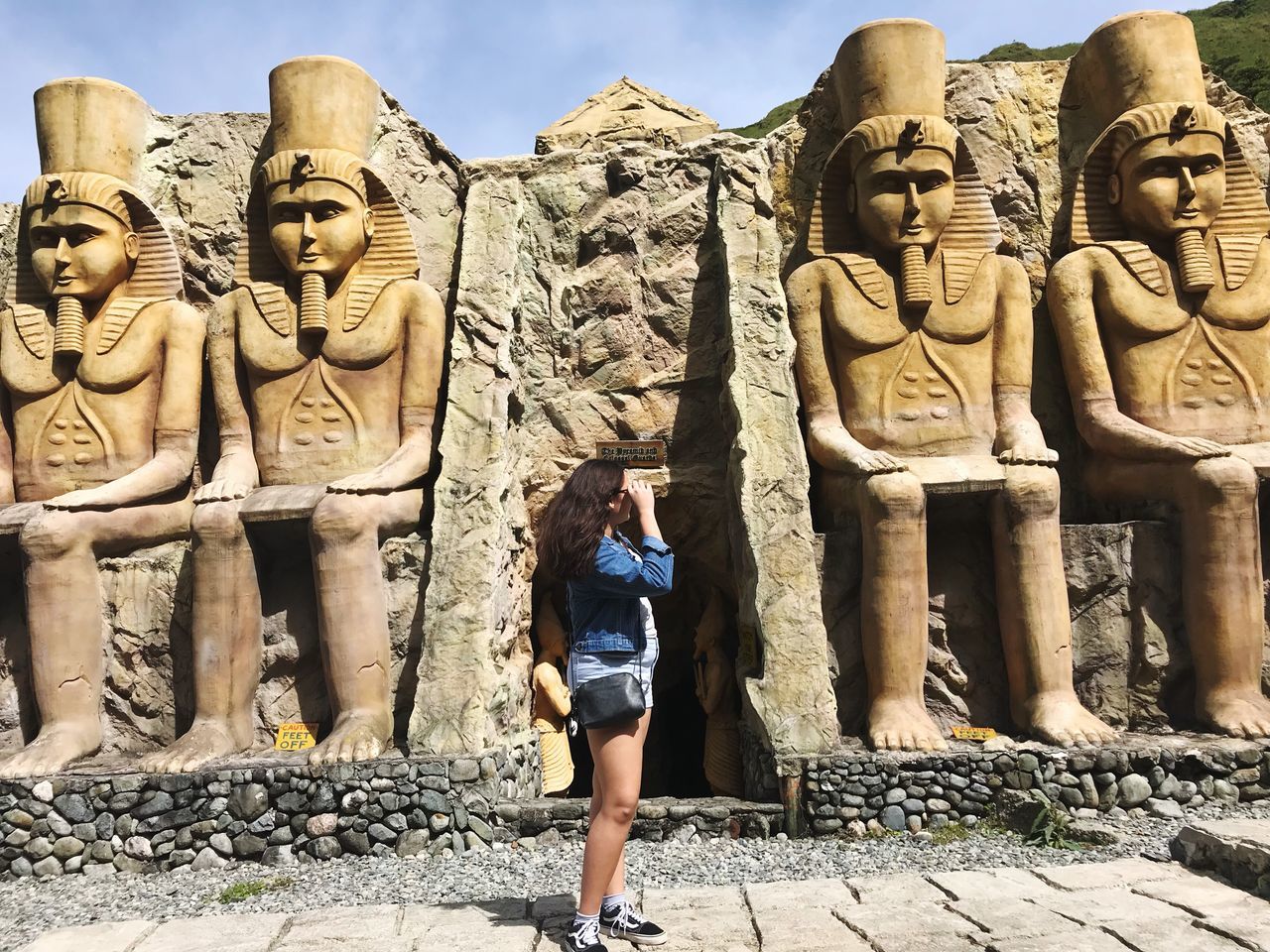 real people, leisure activity, lifestyles, rear view, rock - object, one person, full length, ancient, day, old ruin, history, casual clothing, outdoors, standing, statue, sculpture, architecture, travel destinations, ancient civilization, women, nature, sky, young adult