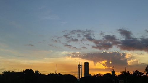 Silhouette trees and buildings against sky during sunset