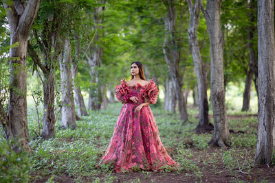 Woman standing by tree in forest